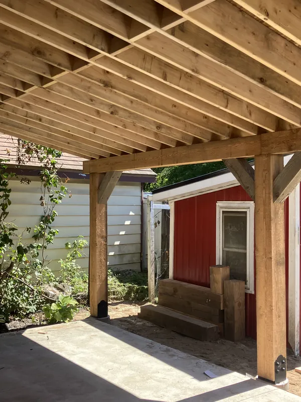 Timber posts, beams, and knee braces under a covered patio roof