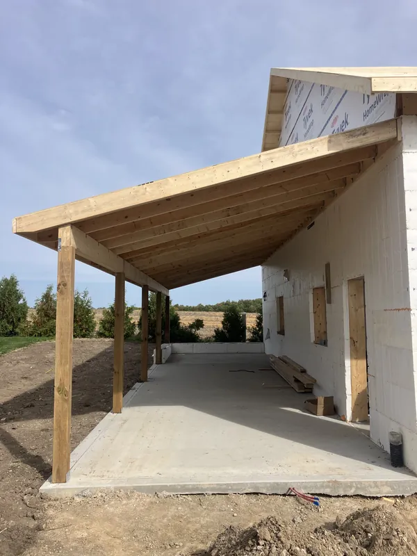 Covered porch rafters and posts framed along the side of a new home