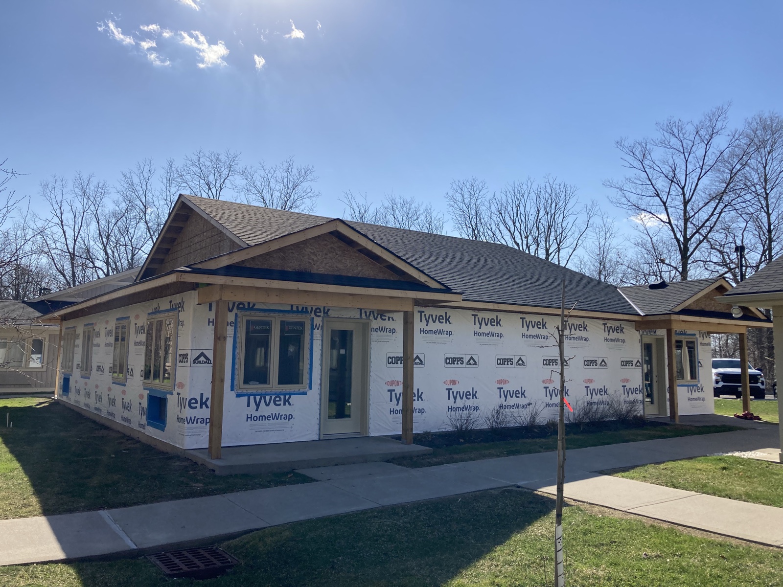 Home addition framing with house wrap, roof work, and porch tie-ins