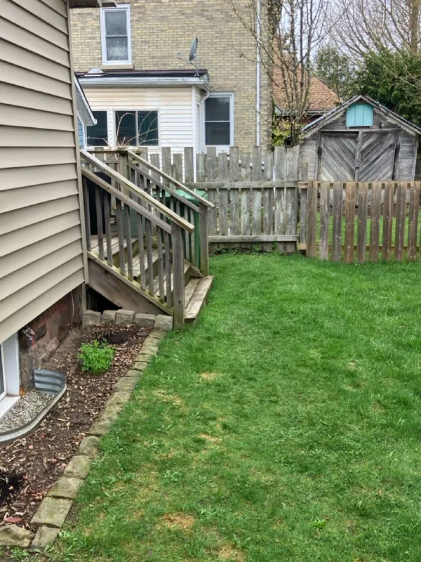 Before: weathered grey stairs and railings coming down onto the lawn at the side of the house