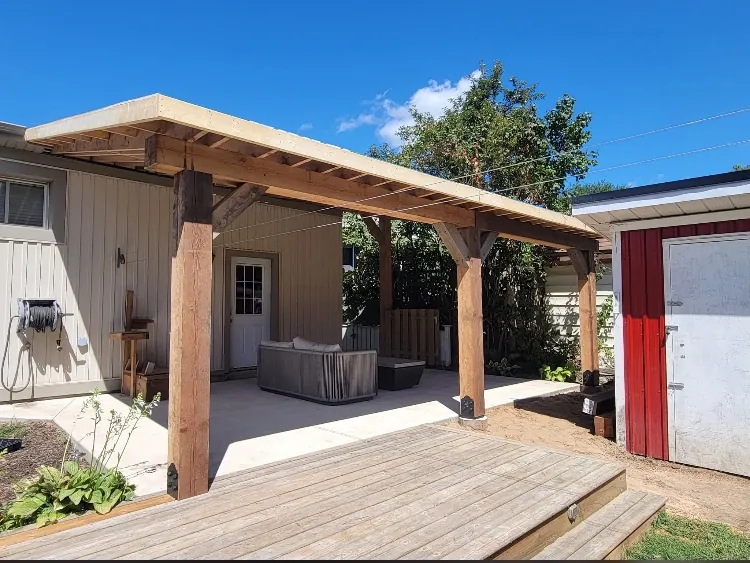 Timber-frame covered patio over a concrete pad, with a wood deck in front